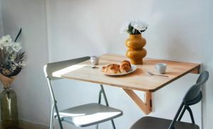 a table with a plate of croissants and a vase at Le petit coin vert de Paris in Montreuil