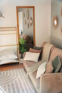 a living room with a couch and a mirror at Le petit coin vert de Paris in Montreuil
