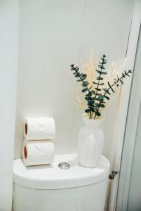 a white vase on top of a toilet with a plant at Le petit coin vert de Paris in Montreuil