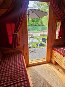una stanza con veranda con tavolo e ombrellone di Schlaf-Fässer am Campingplatz Lienheim a Hohentengen