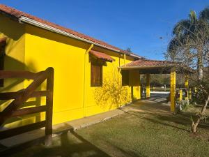 a yellow house with a fence in front of it at Sítio Vista da Serra in Lavrinhas