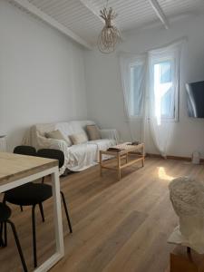 a white living room with a couch and a table at Sea You Soon & Spa 1 in Methana