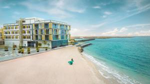 米尔费Beach Bay Hotel Mirfa的站在建筑物旁的海滩上的人