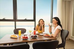 two women sitting at a table drinking coffee at Beach Bay Hotel Mirfa in Al Marfaʼ