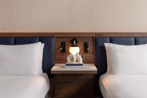 a hotel room with two beds and a lamp on a table at Hilton London Metropole in London