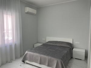 a white bedroom with a bed and a window at Zerbi House in Reggio Calabria