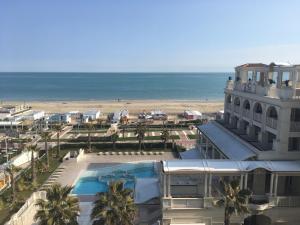 a building with a swimming pool next to a beach at Hotel Corallo in Riccione