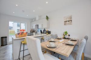 海尔New Harveys Yard By Signature Stays - New Hayle Luxury Stay - Walk to Beach - Sleeps 6的配有木桌椅的厨房和餐厅