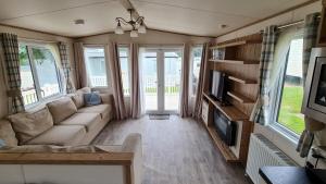 Una sala de estar con un sofá y un televisor. en Hoburne Devon Bay Fabulous 3 bedroom caravan, with decking, en Goodrington