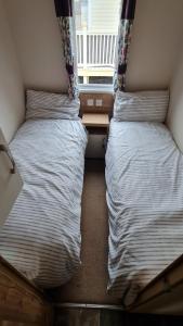 Habitación pequeña con 2 camas individuales y ventana en Hoburne Devon Bay Fabulous 3 bedroom caravan, with decking, en Goodrington 8 fotos más