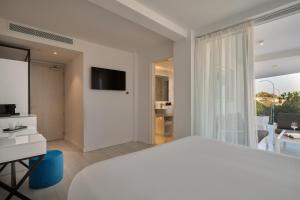 a white bedroom with a large bed and a television at Hotel Napa Suites (Adults Only) in Ayia Napa