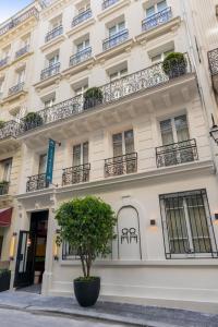 un bâtiment blanc avec un arbre devant lui dans l'établissement Hôtel Adèle & Jules, à Paris