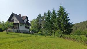 a house on a grassy field with trees at River Lodge Jesenica in Lička Jesenica