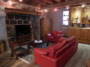a living room with a red couch and a fireplace at La Maison De Marie in Murat