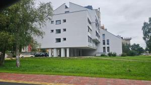 a white building on a grassy field next to a building at Apartamentai Vanagupės banga in Palanga