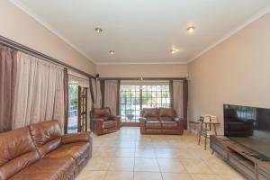 a living room with leather furniture and a flat screen tv at Paradise On Water Road in Gqeberha
