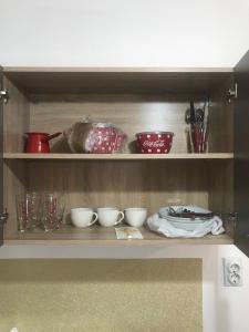 a shelf with bowls and utensils in a kitchen at Riseup apartman in Niš