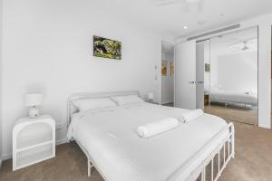 a white bedroom with a white bed and a mirror at The Cotton Tree - Luxury 3BR Apt Pool Gym BBQ Free Prkg 1min to Beach in Maroochydore
