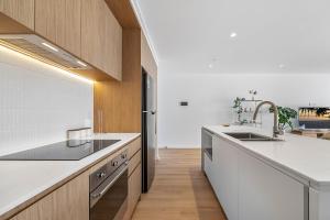 a kitchen with white countertops and wooden cabinets at The Cotton Tree - Luxury 3BR Apt Pool Gym BBQ Free Prkg 1min to Beach in Maroochydore