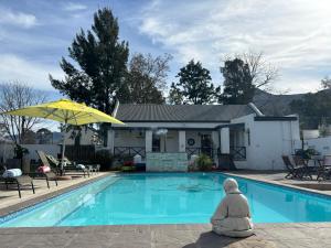 a pool in front of a house with a yellow umbrella at Greyton Toad Hall in Greyton +2 photos
