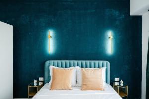 a bedroom with a blue wall and a bed with pillows at Premium Tulip Aparthotel close to Airport & Therme in Tunari