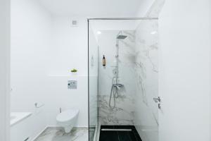 a white bathroom with a shower and a toilet at Premium Tulip Aparthotel close to Airport & Therme in Tunari +158 photos