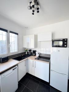 a kitchen with white cabinets and a white refrigerator at Maison entiere jacuzzi reception ouverte 7 7j et 24 24h in Ambarès-et-Lagrave