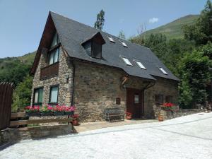 a stone house with a roof with windows and flowers at Apartamento con jardin en Gessa in Gessa