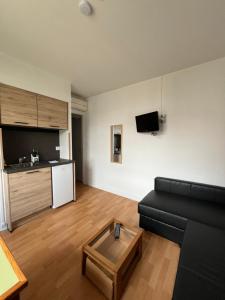 a living room with a black couch and a table at Studio Climatisé au centre ville in Digoin