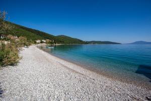 a beach with blue water and a rocky shore at Apartment Pogled na luku in Cres