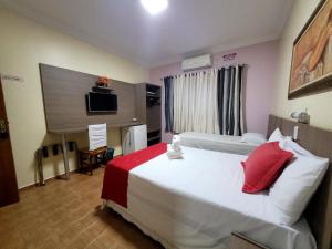 a hotel room with a large bed with red pillows at Hotel CANTO DA SERRA in Caldas Novas