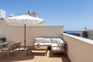 a patio with a couch and an umbrella on a roof at Casa Fina in Estepona