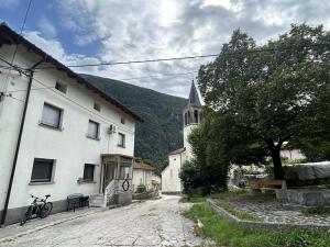 a white building and a church with a tree at Apartment Tonc in Kobarid