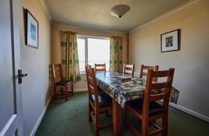 a dining room with a table and chairs and a window at Bungalow with stunning views over Widemouth Bay in Widemouth Bay +18 photos