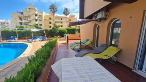 een patio met stoelen en een zwembad en een gebouw bij Casa Amarela - Albufeira in Albufeira