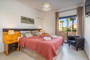 a bedroom with a bed and a chair and a window at Spacious & Sunny Apartment with Pool by HostWise in Portimão