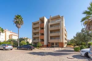 a building with cars parked in a parking lot at Spacious & Sunny Apartment with Pool by HostWise in Portimão