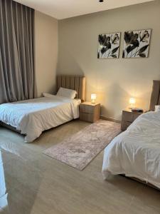 een slaapkamer met 2 bedden en 2 lampen en een tapijt bij Luxury Apartment with 3 bed room in Al Khobar +10 foto's