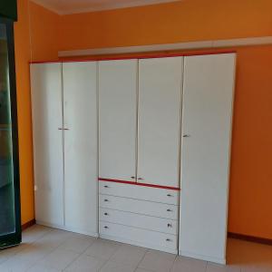 a closet with white cabinets and an orange wall at Casa Zàgará in Schisò
