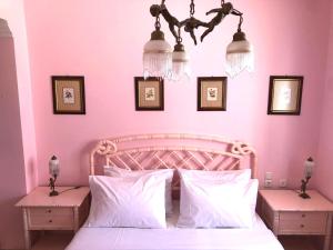 a bedroom with pink walls and a bed with white pillows at Villa Zante Estrella in Kalamaki