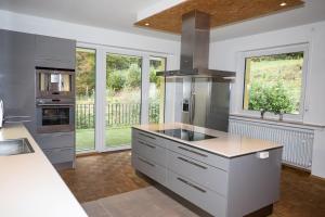 a kitchen with white counters and stainless steel appliances at Whirlpool, Billiard, Sauna! Ferienhaus Lacher in Baiersbronn
