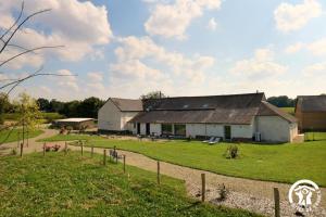 a large white barn with a grassy field in front of it at Les insolites de sophie in Boisgervilly