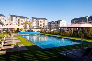 a swimming pool with umbrellas and some buildings at #AlimamaSpaces Manson's Fynbos Villa in Cape Town