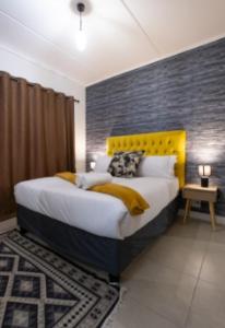 a bedroom with a large bed with a yellow headboard at #AlimamaSpaces Manson's Fynbos Villa in Cape Town +26 photos