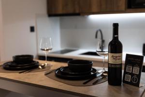 a bottle of wine sitting on a kitchen counter with glasses at Aesthe Suites Noir in Xanthi