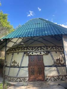 Una pequeña casa con techo verde y una puerta. en Traditional kyrgyz yurt, en Karakol