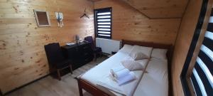 a bedroom with a bed and a desk in a cabin at La Ianis in Vatra Dornei