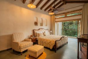 a bedroom with a bed and a chair and a window at Amayah Tattva 3 BHK Escape With Steam Room, Open Shower & Private Pool in Assagao