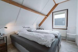 une chambre avec deux lits avec des draps blancs et une fenêtre dans l'établissement Vakantiehuis Mosselbank 22, loopafstand van strand VP070, à Ouddorp