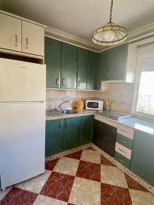 a kitchen with green cabinets and a white refrigerator at La Torre in Tózar